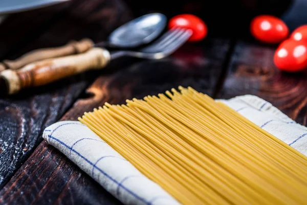 Ham İtalyan makarna spagetti ve koyu ahşap masa kiraz domates