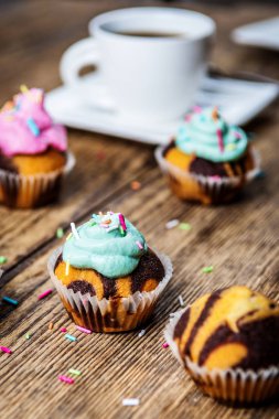 Renkli pembe ve yeşil ahşap masa üzerinde krem ile çikolatalı kek