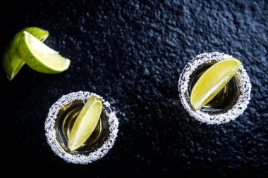 Geleneksel Meksika tekila ile limon, limon, tuz ve buz küp üzerinde karanlık taş tablo tablo üstten görünüm