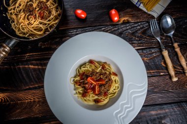 Geleneksel İtalyan makarna spagetti bolognese kıyma ve koyu ahşap masa üstü görünümü domates ile