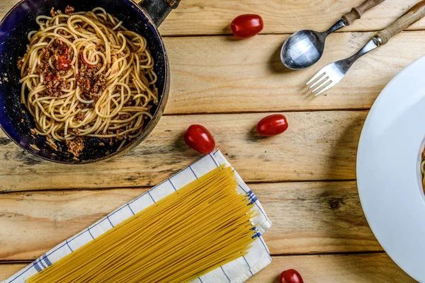 Geleneksel İtalyan makarna spagetti bolognese kıyma ve ahşap masa üstü görünümü domates ile