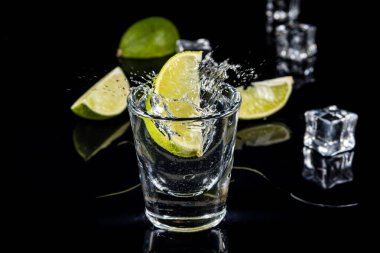 Ice cube siyah zemin üzerine geleneksel Meksika tekila sıçrama kireç.