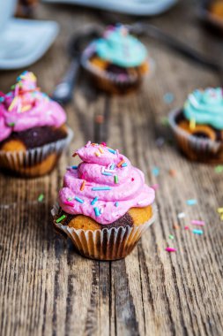 Renkli pembe ve yeşil ahşap masa üzerinde krem ile çikolatalı kek