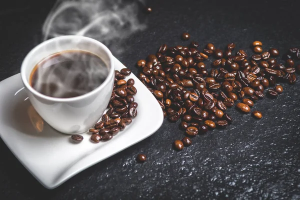 Beyaz duman ve kahve fasulye siyah taş masada sıcak kahve fincan