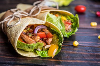 Geleneksel Meksika tortilla şal koyu ahşap masa üzerinde ızgara tavuk eti ve sebze ile