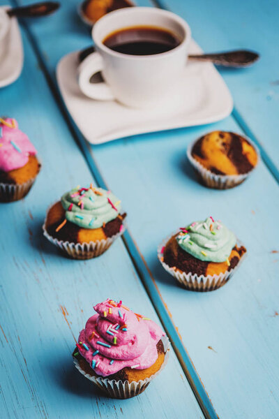 Chocolate cupcake with colored pink and green cream on blue table