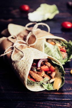 Geleneksel Meksika tortilla şal koyu ahşap masa üzerinde ızgara tavuk eti ve sebze ile