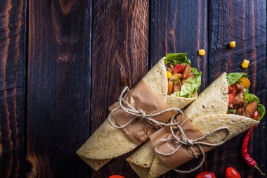 Geleneksel Meksika tortilla şal koyu ahşap masa üzerinde ızgara tavuk eti ve sebze ile