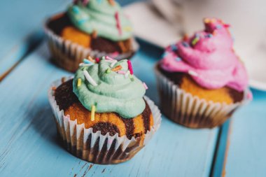 Renkli pembe ve yeşil mavi masada krema ile çikolatalı kek