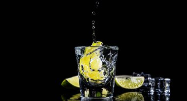 Ice cube siyah zemin üzerine geleneksel Meksika tekila sıçrama kireç.