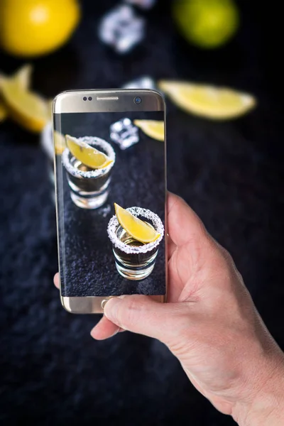 Man taking photo of Tequila with lemon