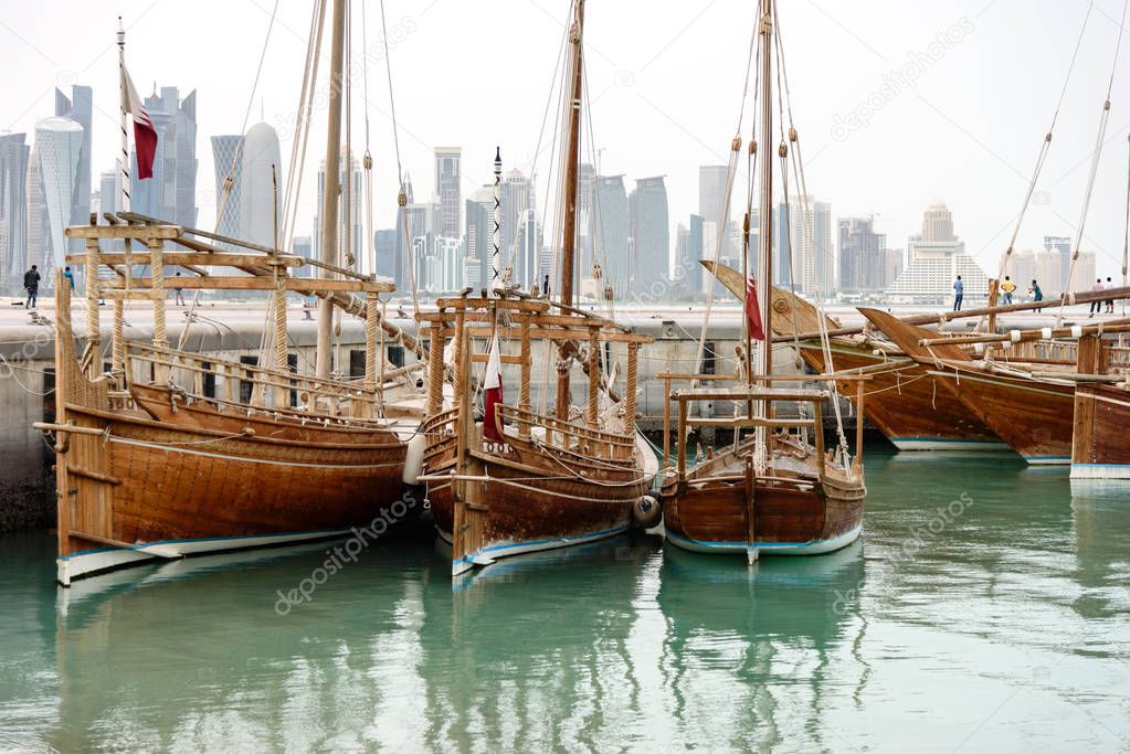 Traditional dhows with flags of Qatar are docked in harbor of Doha, such vessels are popular for tourist trips along the coast, Qatar, Middle East.