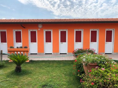 Üzerinde çiçekler ve yeşil çimenler olan turuncu plaj kabinleri. Plaj tatil yeri. 