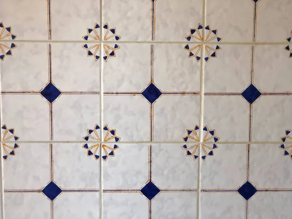 White and blue tiles on floor close-up. White tiles with ornament. Interior design. Background