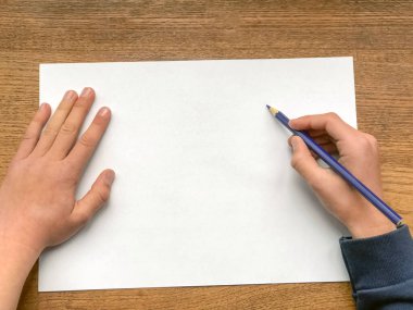 Yazmaya ya da çizmeye hazır beyaz kağıt üzerine kalemle çocuk elleri. Yakın plan. Uzayı kopyala Eğitim konsepti. Öğrenme