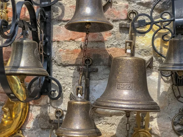 Different old metal small bells on the brick wall close-up.