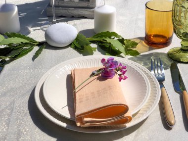 Beyaz tabaklar, pembe peçeteler ve süslemelerle süslü beyaz masa. Düğün masası, restoran.