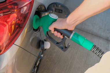 Adamın elleri benzin pompasını tutuyor ve arabayı yakına dolduruyor. Enerji endüstrisi. Benzin istasyonu iş / pazar.