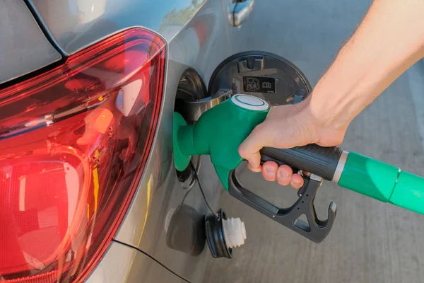Adamın elleri benzin pompasını tutuyor ve arabayı yakına dolduruyor. Enerji endüstrisi. Benzin istasyonu iş / pazar 