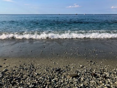 Ufkun karşısındaki sahilde dalgalar ve mavi gökyüzü. Deniz arka planı. Boşluğu kopyala