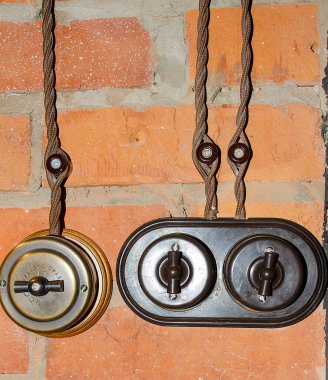 Tuğla duvar arka planında eski usul menteşeli elektrik kabloları ve anahtarlar.
