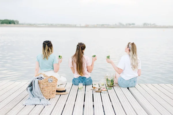 Τρία Κορίτσια Που Κάθονται Μια Ξύλινη Προβλήτα Μπροστά Στο Νερό — Φωτογραφία Αρχείου
