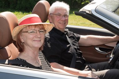 Güneşli bir günde bir lüks Cabrio araba ile iki mutlu yaşlı insanlar