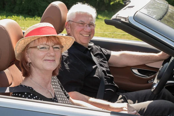 Smiling happy senior couple in the car on a sunny day