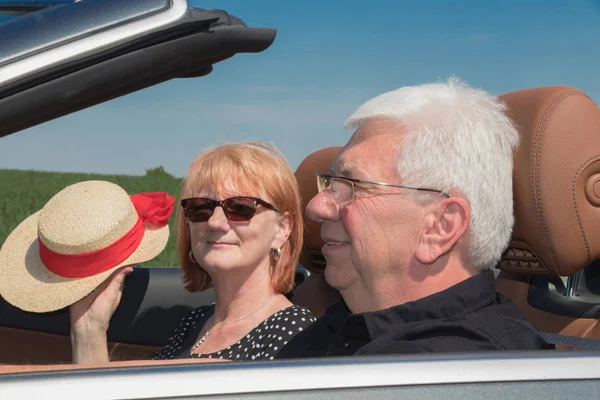 Older couple in a luxury convertible car on a sunny day
