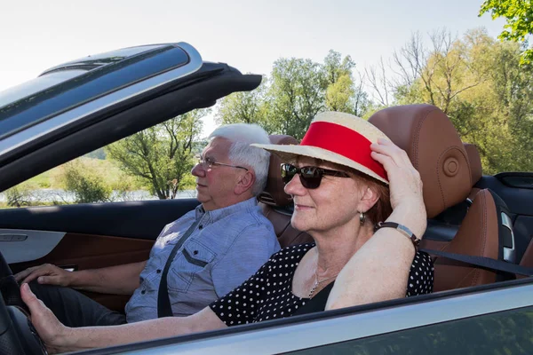 Beautiful older woman with sun hat and her partner in a car