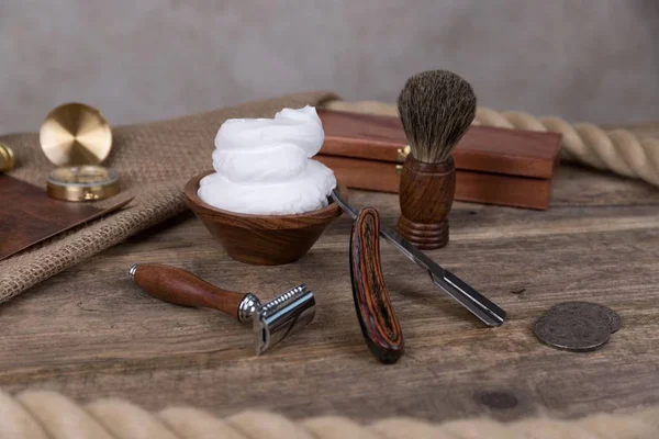 shaving accessories  - wooden razor with shaving brush and shaving foam on a rustic wooden background