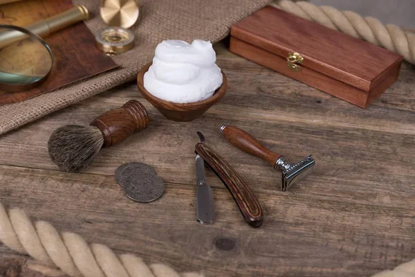 shaving razor with shaving brush and shaving foam on a rustic wooden table - vintage shaving accessories