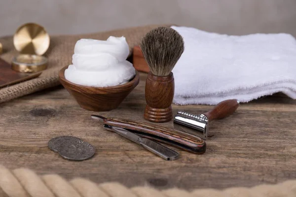 Wooden shaving razor with shaving brush and shaving foam on a rustic wooden background - vintage shaving accessories