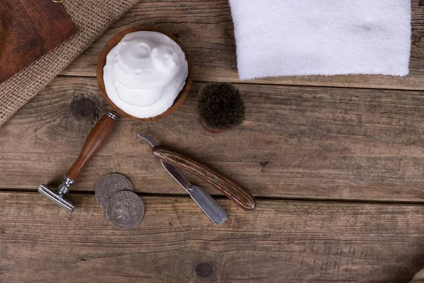 vintage shaving accessories  - wooden razor with shaving brush and shaving foam on a rustic wooden table - top view