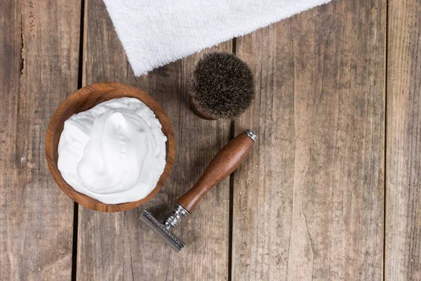 vintage shaving accessories  - wooden razor with shaving brush and shaving foam on a rustic wooden table