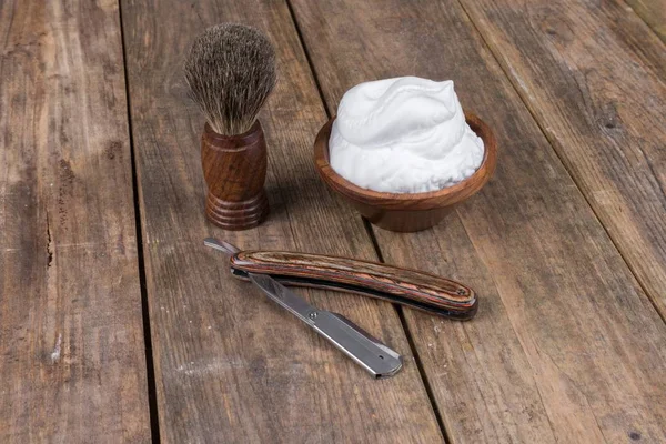 shaving accessories  - wooden razor with shaving brush and shaving foam on a rustic wooden table