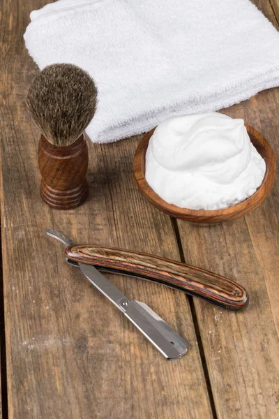 shaving accessories  - wooden razor with shaving brush and shaving foam on a rustic wooden table