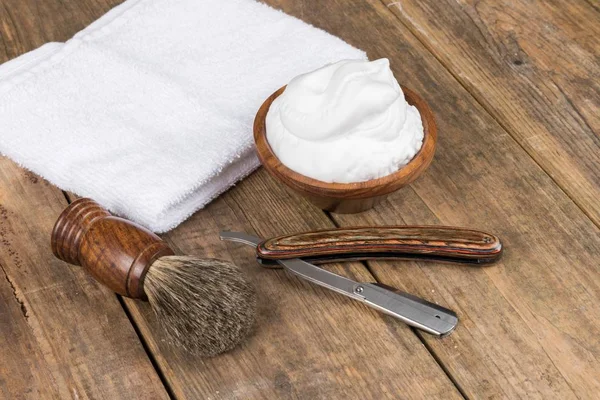 shaving accessories  - wooden razor with shaving brush and shaving foam on a rustic wooden table