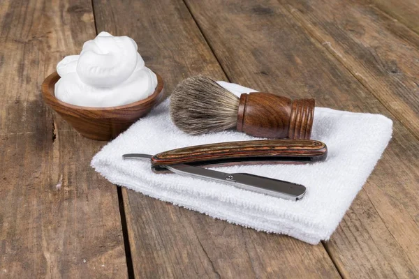Wooden shaving razor and shaving brush with shaving foam on a white background