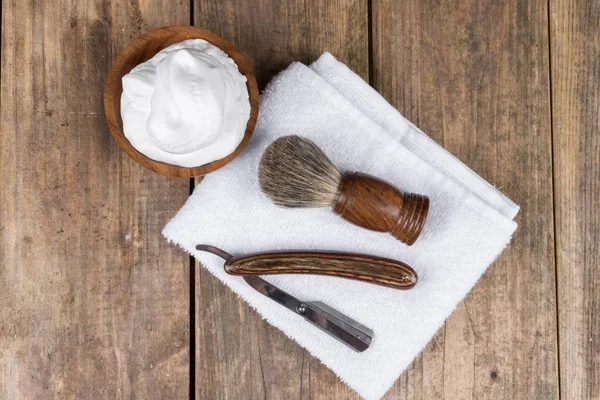 Wooden shaving razor and shaving brush with shaving foam on a white background