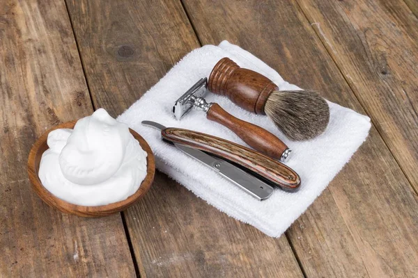 shaving accessories  - wooden razor with shaving brush and shaving foam on a rustic wooden table