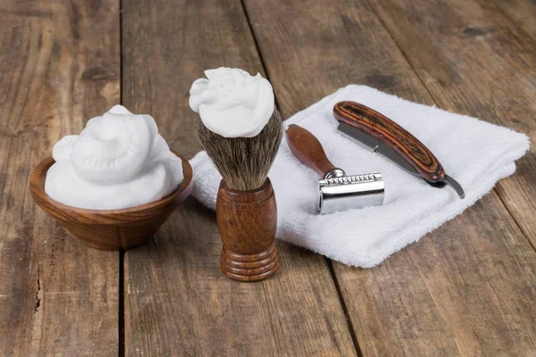 shaving accessories  - wooden razor with shaving brush and shaving foam on a rustic wooden table