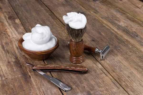 shaving accessories  - wooden razor with shaving brush and shaving foam on a rustic wooden table