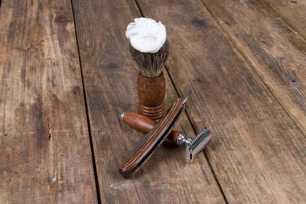 shaving accessories  - wooden razor with shaving brush and shaving foam on a rustic wooden table