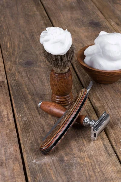 shaving accessories  - wooden razor with shaving brush and shaving foam on a rustic wooden table