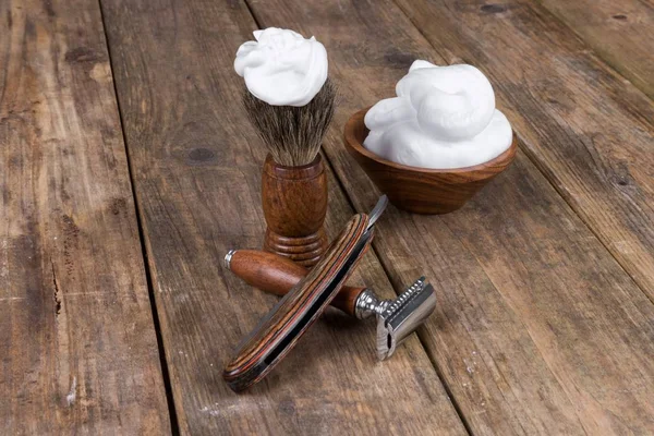 shaving accessories  - wooden razor with shaving brush and shaving foam on a rustic wooden table