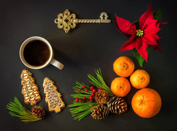 Yılbaşı yeni yıl natürmort düz lay bir Noel yıldızı, mandalina, portakal, çam kozalakları, çobanpüskülü çilek, tanımlama bilgileri, Çamın dalları ile bir oyuncak anahtar ve bir fincan sıcak kahve çay siyah arka plan üzerine