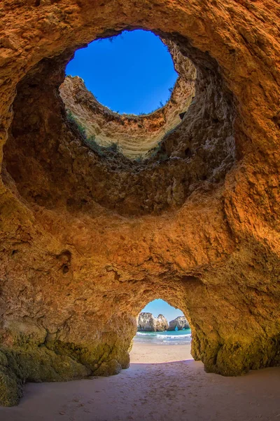 Famous beach rock oluşumunda Algarve, Portekiz mağaralar. Bir mağaraya okyanus görebilirsiniz. Mağara tavandaki delikten mavi gökyüzü görebilirsiniz