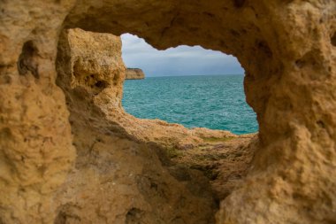 Atlantik Okyanusu mavi su ve Algarve, Portekiz karşı kıyıda uçurumun üzerinden gördüğünüz sarı rock, bir mağarada deliktir.