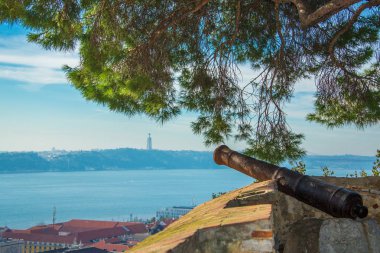 Lizbon, Portekiz of St. George kale duvarında bir ağacın altında eski top. River Tagus görünümünü / rio Tejo ve İsa heykeli